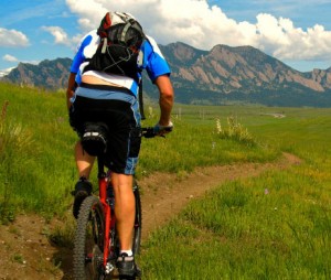 Man mountain biking towards Boulder Flatirons
